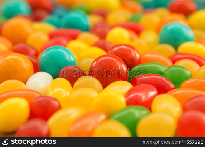 Colorful jelly beans of different sizes close to wallpaper