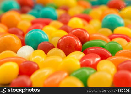 Colorful jelly beans of different sizes close to wallpaper