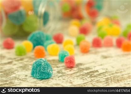 Colorful jelly beans on the wooden background. Focus on foreground