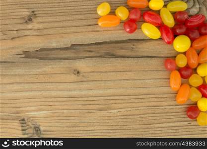 Colorful jelly beans shaped a frame to write your text on a wooden background