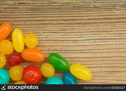 Colorful jelly beans shaped a frame to write your text on a wooden background