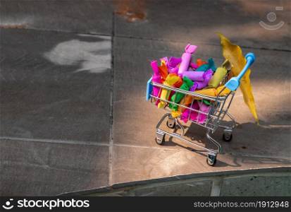 Colorful Jelly toffee in shopping cart on tiles floor. Giving happiness, Happy holidays, Selective focus.