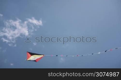 Colorful kite flying in sunny summer blue sky. Toy for children fun, leisure activity, recreation. Slow motion, slow-motion, slowmo, slowmotion. Copy space