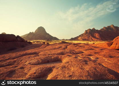 Colorful landscapes of the orange rocks in the Spitscoppe mountains in Namibia on a sunny hot day.