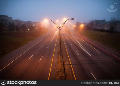 Colorful light traces of busy night traffic on highway. Atlanta city street, foggy autumn weather, GA, USA