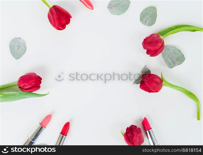Colorful lipsticks and flowers flat lay frame. Colorful make up flat lay scene