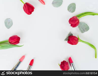 Colorful lipsticks and flowers flat lay frame. Colorful make up flat lay scene