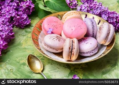 Colorful macarons cake and branch of lilac blossoms. Spring dessert from french macaroons