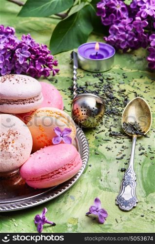 Colorful macarons cake and branch of lilac blossoms. Sweet french macaroons
