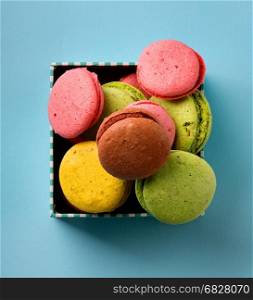 Colorful macarons in a gift box on blue background