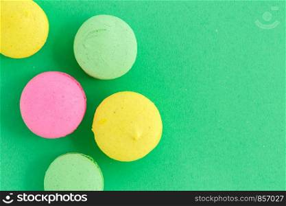colorful macarons or macaroons cookies on green background. top view