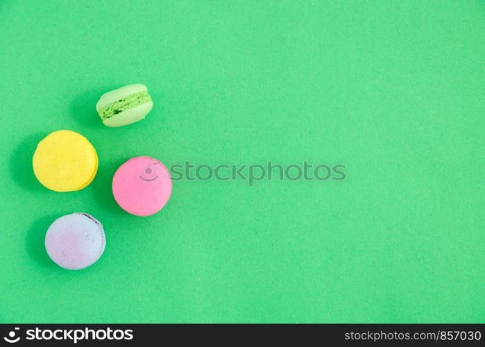 colorful macarons or macaroons cookies on green background. top view