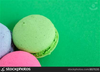 colorful macarons or macaroons cookies on green background. top view
