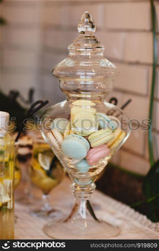 Colorful macarons stand in round transparent weight as part of candy bar sweet table. Colorful macarons stand in round transparent weight as part of candy bar sweet table. French macaroons. Candy bar.