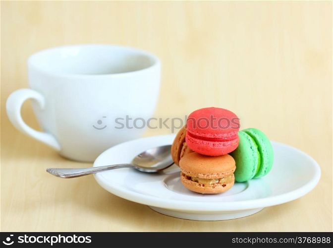 Colorful macaroons and a cup of coffee with spoon
