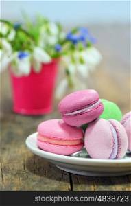 Colorful macaroons and spring flowers on wooden table