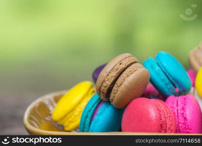 Colorful Macaroons in dish on wooden table in garden