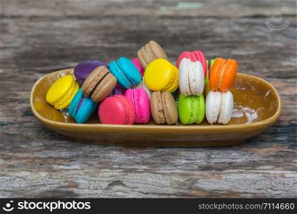 Colorful Macaroons in dish on wooden table in garden