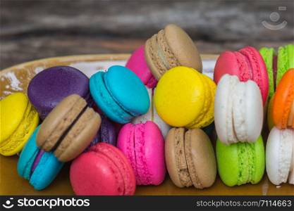 Colorful Macaroons in dish on wooden table in garden