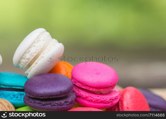 Colorful Macaroons in dish on wooden table in garden