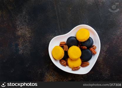 colorful macaroons with dry pecan in bowl
