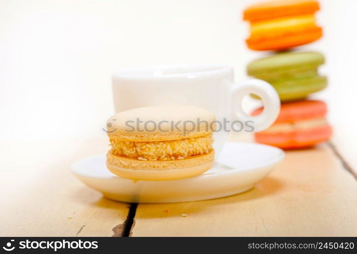 colorful macaroons with espresso coffee over white wood table