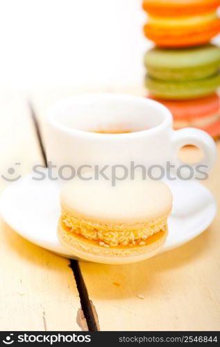 colorful macaroons with espresso coffee over white wood table