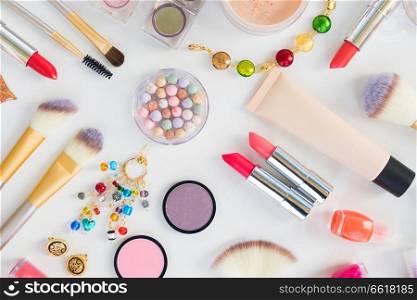 Colorful make up and brushes products top view flat lay pattern on white background. Colorful make up flat lay scene