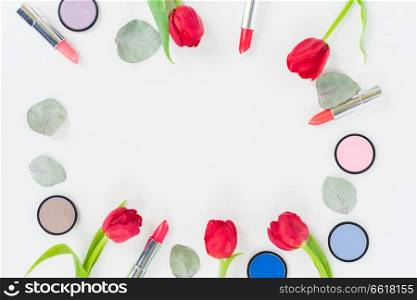 Colorful make up and tulips flat lay frame with copy space. Colorful make up flat lay scene