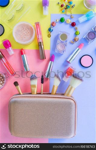 Colorful make up products with golden pursue material design top view flat lay scene. Colorful make up flat lay scene