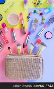 Colorful make up products with golden pursue material design top view flat lay scene. Colorful make up flat lay scene