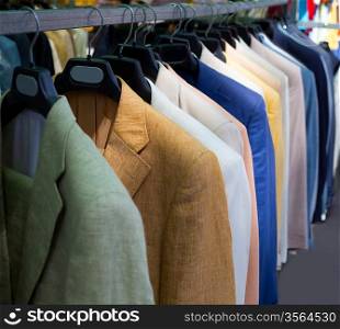 colorful male suits in row in a hanger as a pattern