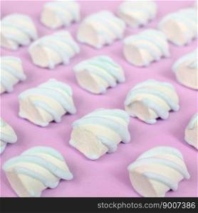 Colorful marshmallow laid out on pink paper background. pastel creative textured pattern. Perspective macro shot.. Colorful marshmallow laid out on pink paper background