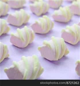 Colorful marshmallow laid out on violet paper background. pastel creative textured pattern. Perspective macro shot.. Colorful marshmallow laid out on violet paper background. pastel creative textured pattern. Perspective macro shot