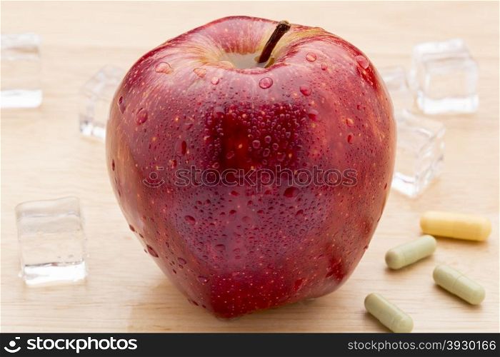 Colorful medicine capsules and red apple. Colorful medicine capsules and red apple on wooden background