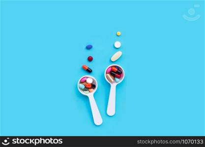 Colorful medicine pills, tablets and capsules on blue background. Copy space