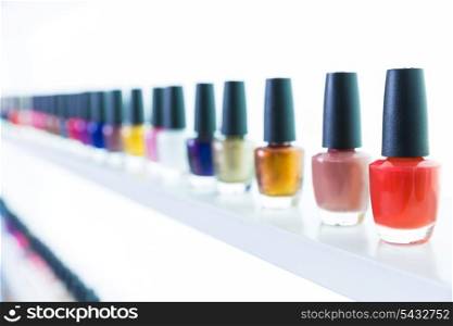 colorful nail polish colors in a row at nails saloon on white background