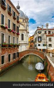 Colorful narrow lateral canal, church Santa Maria dei Miracoli and pedestrian bridge in the sestiere of Cannaregio at morning, in Venice, Italia