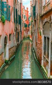 Colorful narrow lateral canal in Venice with docked boat, Italy
