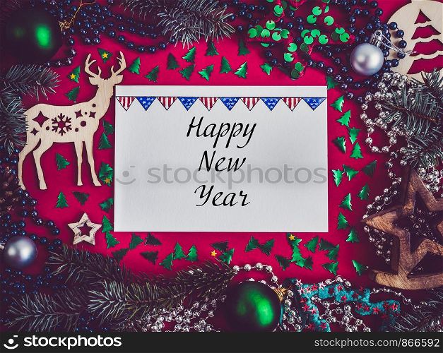 Colorful New Year decorations, silver beads, branches of the Christmas tree, drawing in a notebook on a red surface. Top view, close-up, flat lay. Greeting card. Colorful New Year and Christmas decorations. Greeting card
