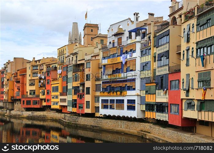Colorful old houses reflected in water river Onyar, Basilica of Sant Feliu in Girona, Catalonia, Spain