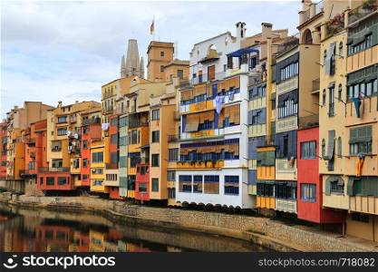 Colorful old houses reflected in water river Onyar, Basilica of Sant Feliu in Girona, Catalonia, Spain