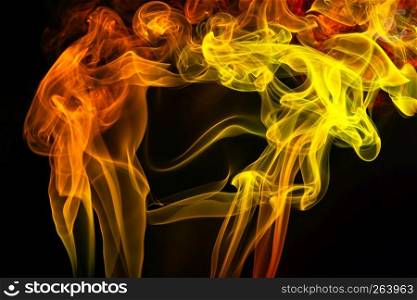Colorful orange and yellow smoke of incence sticks isolated at black background. Colorful smoke of incence stick isolated at black background