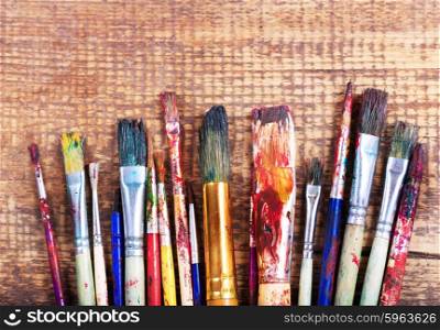 colorful paint brushes on a wooden background
