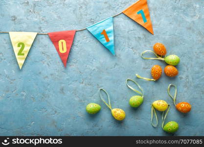 colorful painted Easter eggs and decorations on a light stone background with space for text