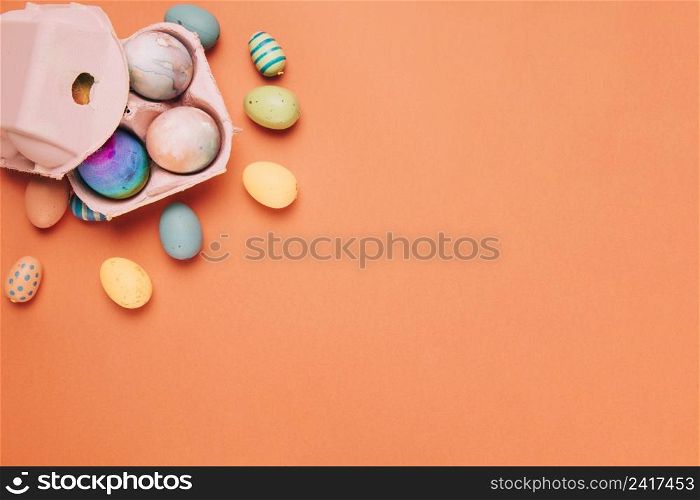 colorful painted easter eggs carton box orange background