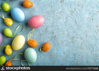 colorful painted Easter eggs on a light stone background with space for text