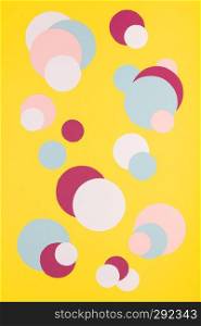Colorful paper circles on yellow paper background, flat lay. Colorful paper circles on yellow paper background