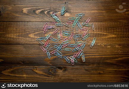 Colorful paperclips and vintage notebook on wooden desk. Background with place for text