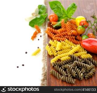 Colorful pasta on a cutting board with tomatoes and spices